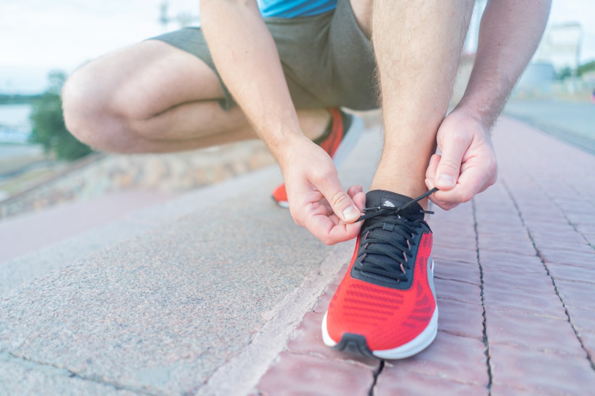 A runner lacing up a pair of red running shoes